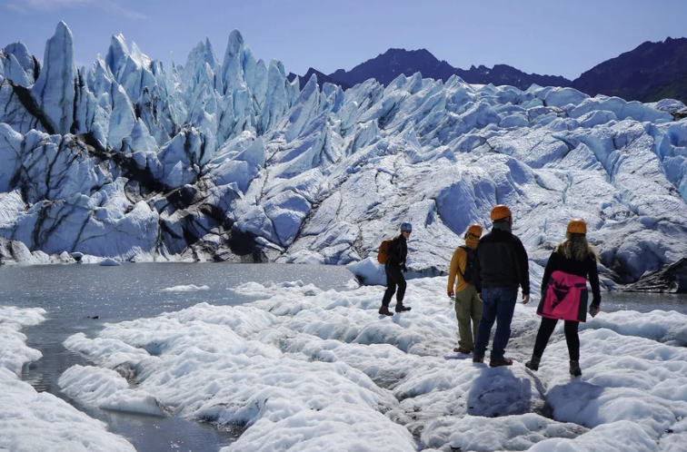 Visitors exploring Matanuska Glacier with dramatic blue ice formations and mountain backdrop